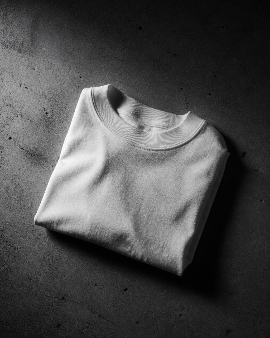 Playera blanca de ¿Why not? doblada sobre concreto oscuro.