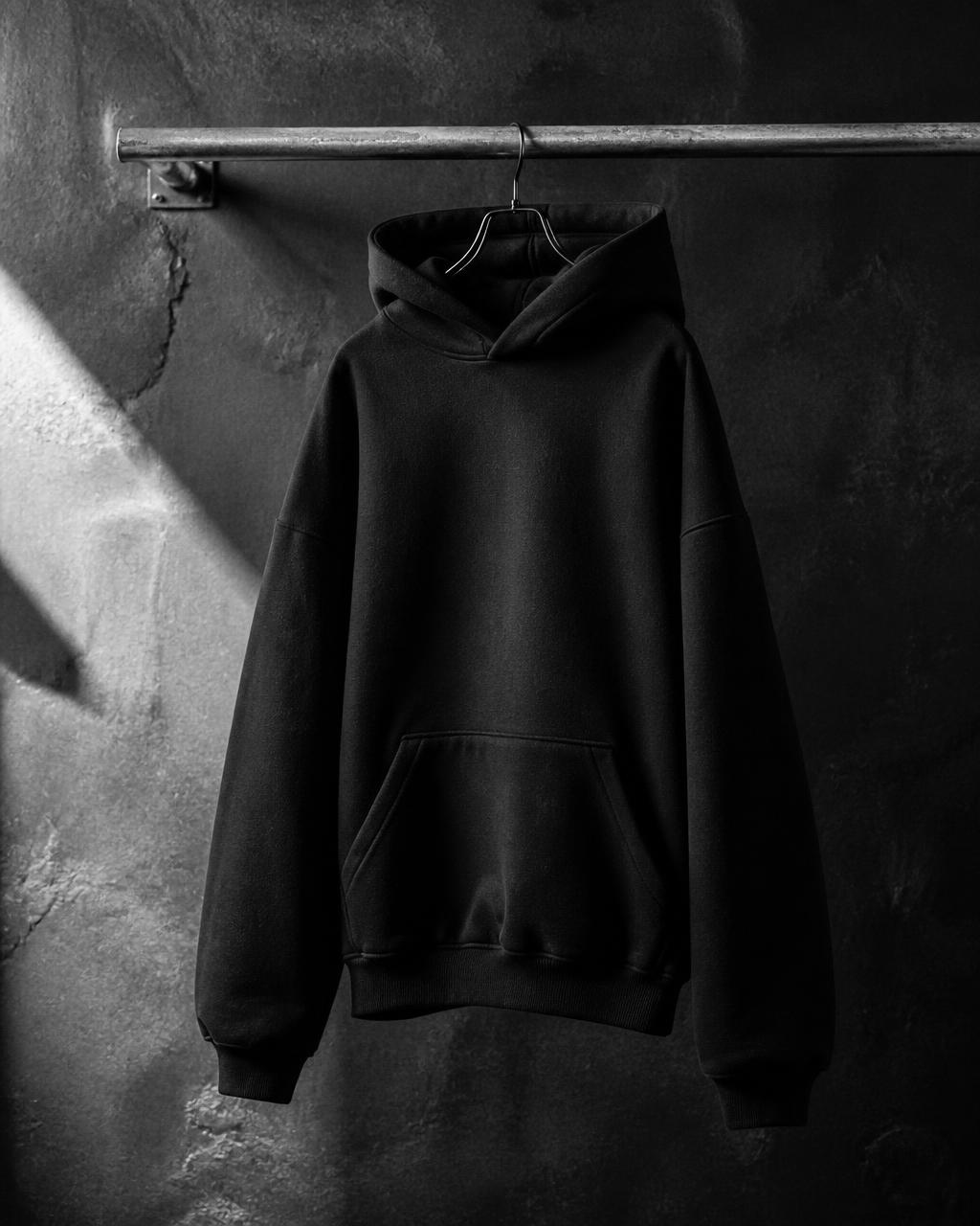 Hoodie negro oversize de ¿Why not? colgado en un tubo metálico.